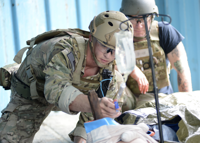 Student in the Special Operations Combat Medic Course at the U.S. Army John F. Kennedy Special Warfare Center and School checks an intravenous bag during field training. 